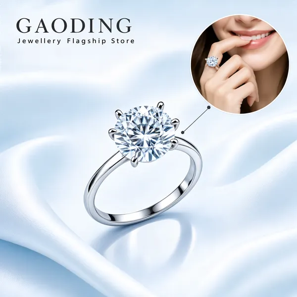 [Format]
Professional e-commerce product main image, square 1:1, icy luxury jewellery advertising style with soft silk backgrounds and a lifestyle inset circle.

[Colors]
Pale ice-blue and white silky background (#dcebf2 to #f6fbfd) with gentle satin folds; brilliant white-silver ring metal; charcoal serif brand type; no frame border.

[Layout]
A charcoal brand lockup sits top-left with a small subline; a circular inset photo hangs upper-right connected by a small pointer; the solitaire ring dominates the centre at a slight angle with a soft reflection beneath.

[Subject]
Centre: a white-gold solitaire engagement ring with a large round brilliant-cut diamond in a six-prong setting, facets sparkling, knife-edge band catching cool light. Inset circle: a close photo of a fair-skinned hand wearing the ring resting near the smiling lips and chin of a fair-skinned woman. No other people.

[Headline]
Top-left in charcoal serif caps: "GAODING" over small spaced caps: "Jewellery Flagship Store".

[Mood]
Pristine, romantic and high-clarity; icy silk blues framing one brilliant diamond moment.