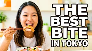A flat, straight-on YouTube thumbnail. A food vlogger mid-reaction on the left third, delighted and holding chopsticks lifting a glistening piece of salmon nigiri toward her mouth. On the right two-thirds, stacked thumbnail text in chunky bold white letters with a thick dark outline: a large top line "THE BEST BITE" and a smaller sub text line beneath it "IN TOKYO." Clean bright palette — fresh oranges, greens, white and cream with soft natural light. High-contrast food-vlogger thumbnail style, crisp detail, no tilt, no 3D perspective.
