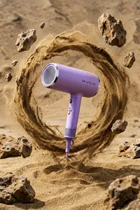 photograph of a lavender-colored flco hairdryer with hair dry text on the barrel, suspended in mid-air amidst a swirling cloud of fine, brown sand, the hairdryer has a round, vented nozzle and a textured grip, surrounding the hairdryer are scattered, irregularly shaped rocks and a sandy, desert-like background, the sand creates a dynamic, circular motion around the hairdryer, adding a sense of movement and contrast to the image, the lighting is natural, highlighting the textures of the sand and rocks, and casting subtle shadows, the overall composition is dynamic and visually striking
